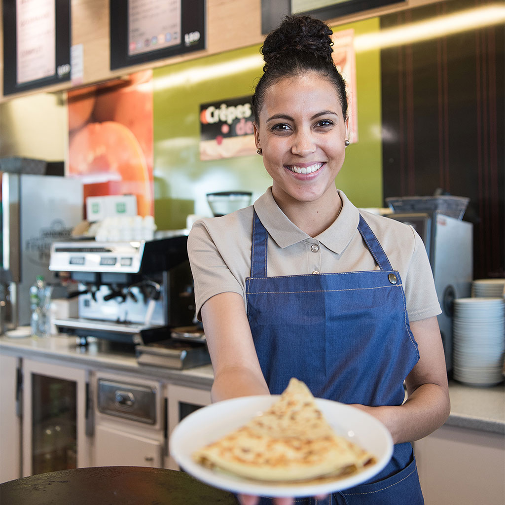 Serveuse montrant une assiette de crêpes au comptoir d'un restaurant